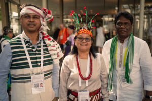 Indigenous pre-assembly gathering at the WCC - two men and a woman in traditional dress
